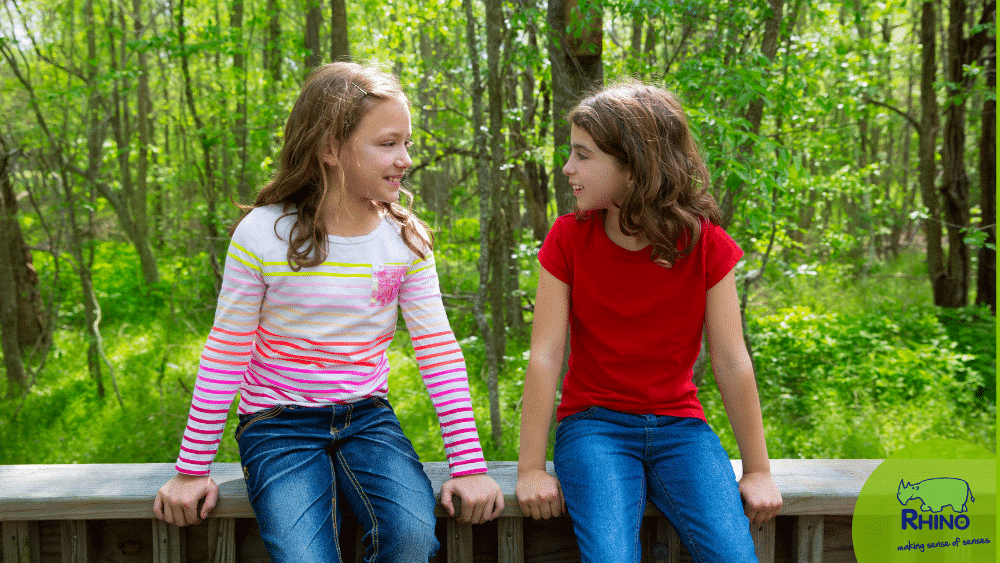 two children talk on a bench in the woods