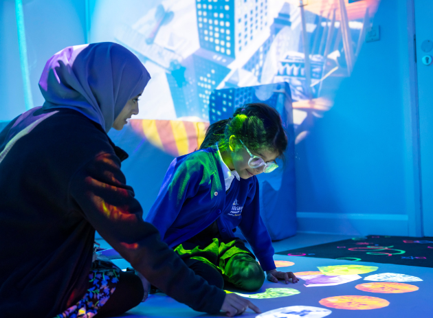 Teacher and a student engaging with an interactive floor projector
