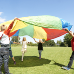Children playing with a colourful parachute outside