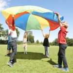 Children playing with a colourful parachute outside