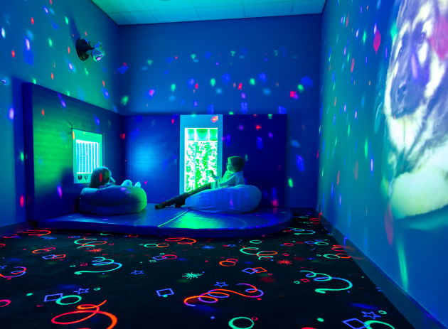 Two children relax inside a calming sensory room.