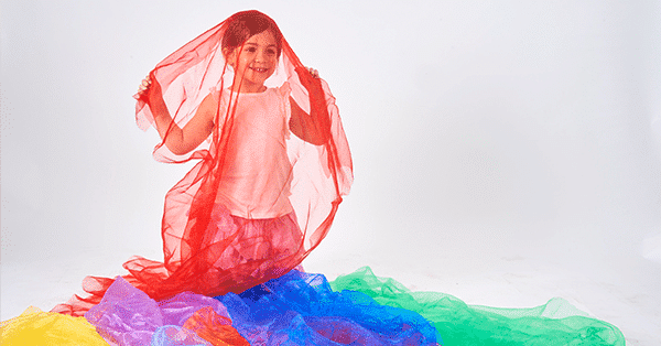 young girl plays with rainbow organza fabric